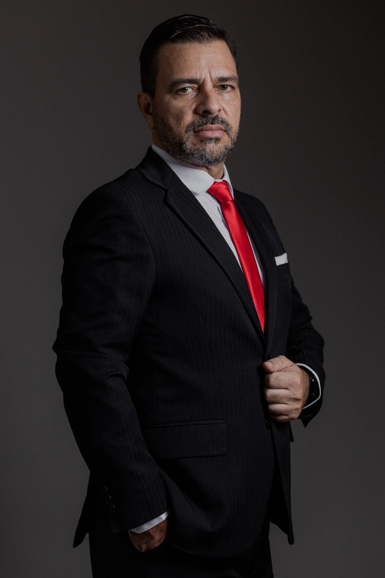 Jorge Inácio em pé, de terno escuro e gravata vermelha